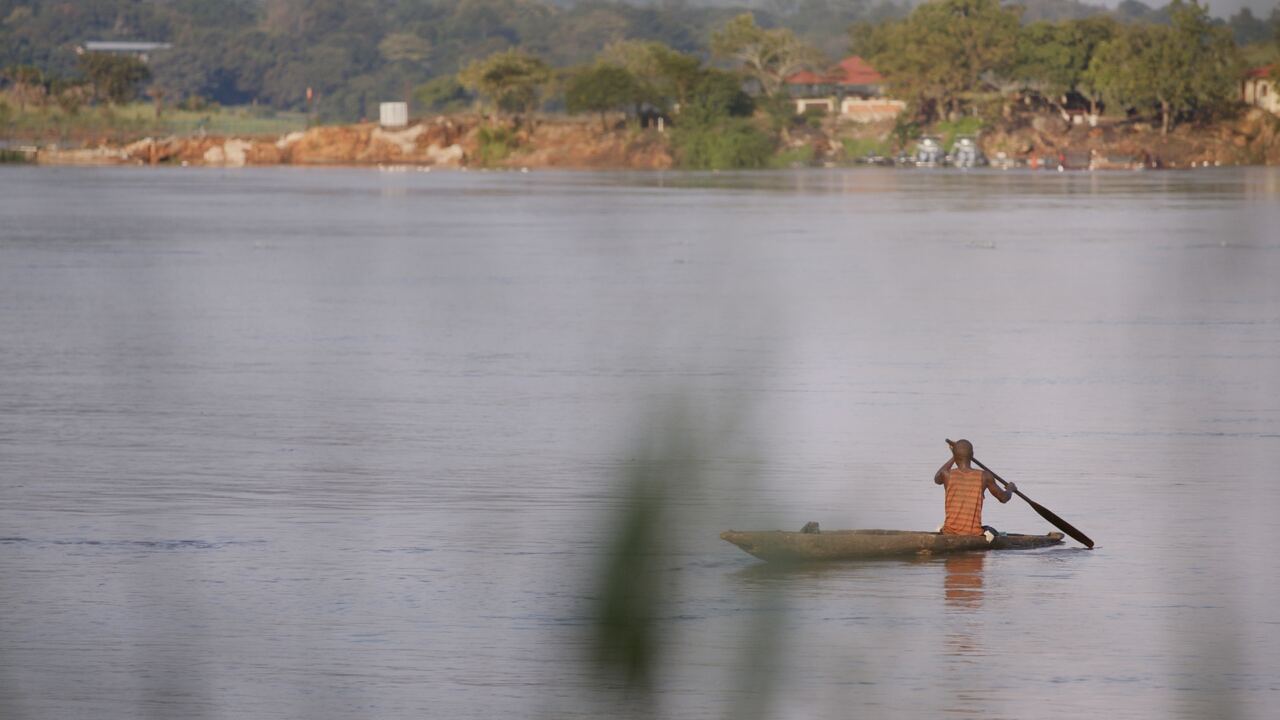 A man paddling a canoe on a wide river