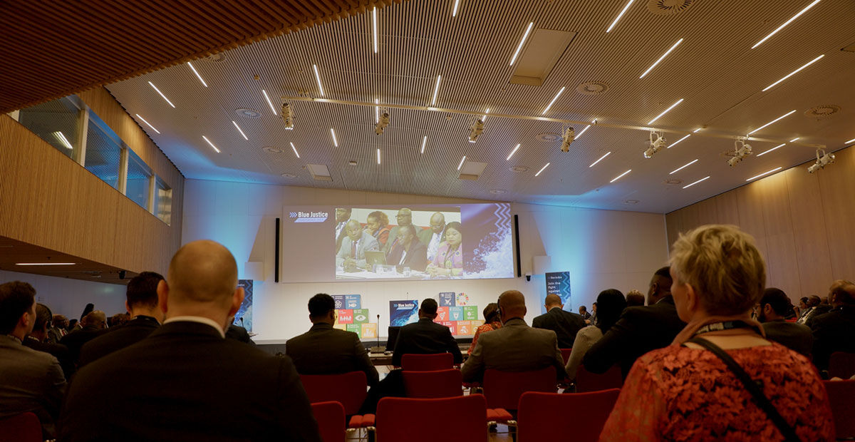 The conference hall at UN City, Copenhagen, with delegates watching the stage screens