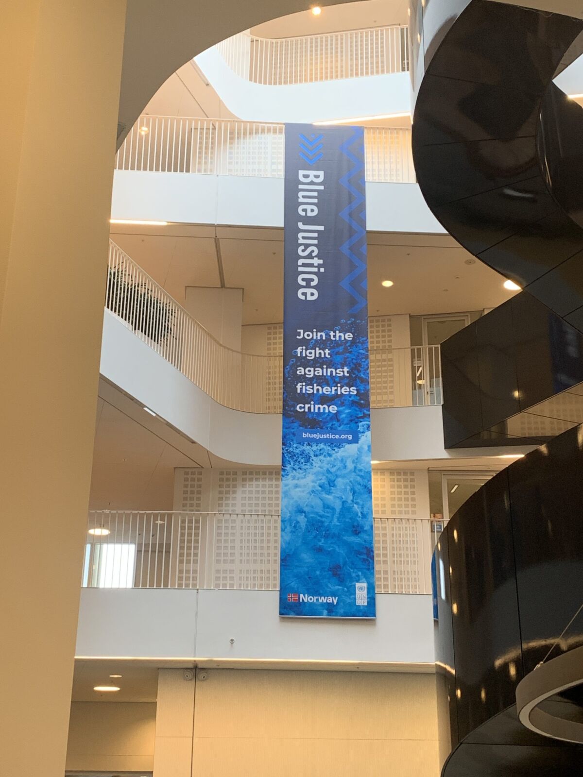 A tall Blue Justice banner hanging in the atrium at UN City
