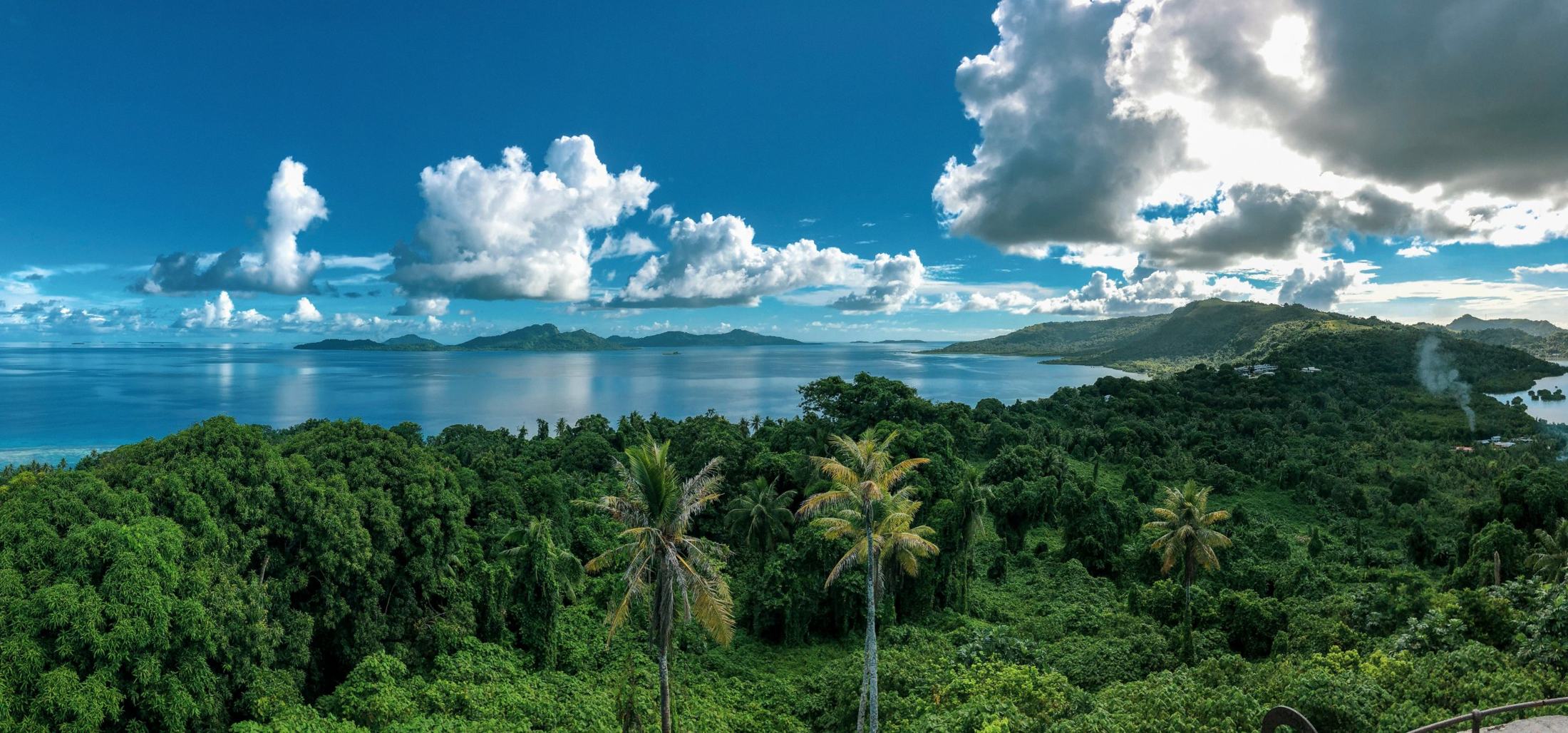 Forested hills above a calm lagoon, with islands on the horizon
