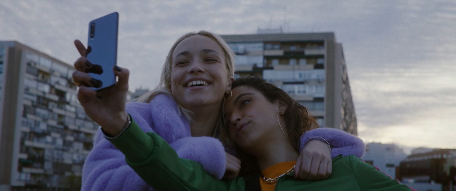 Film still: two young women taking a selfie in a city