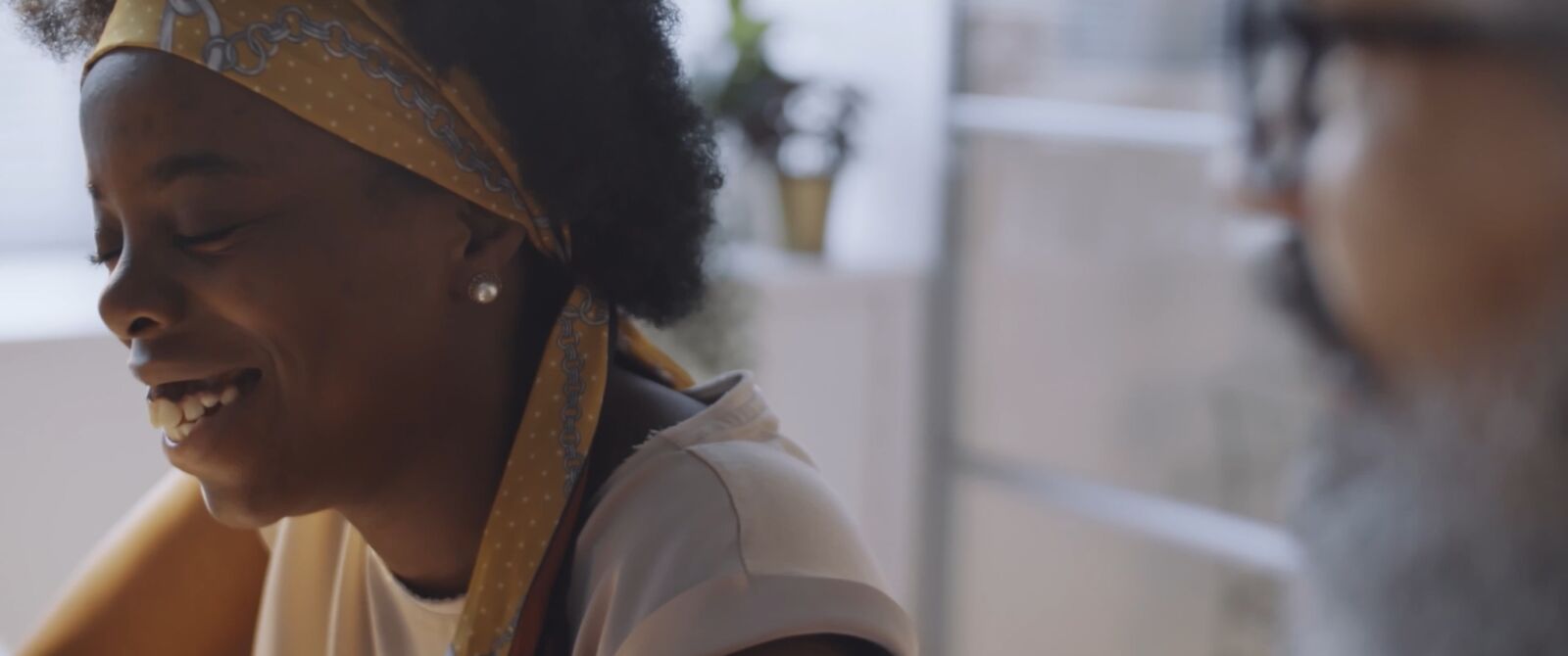 Film still: a young woman smiling in conversation