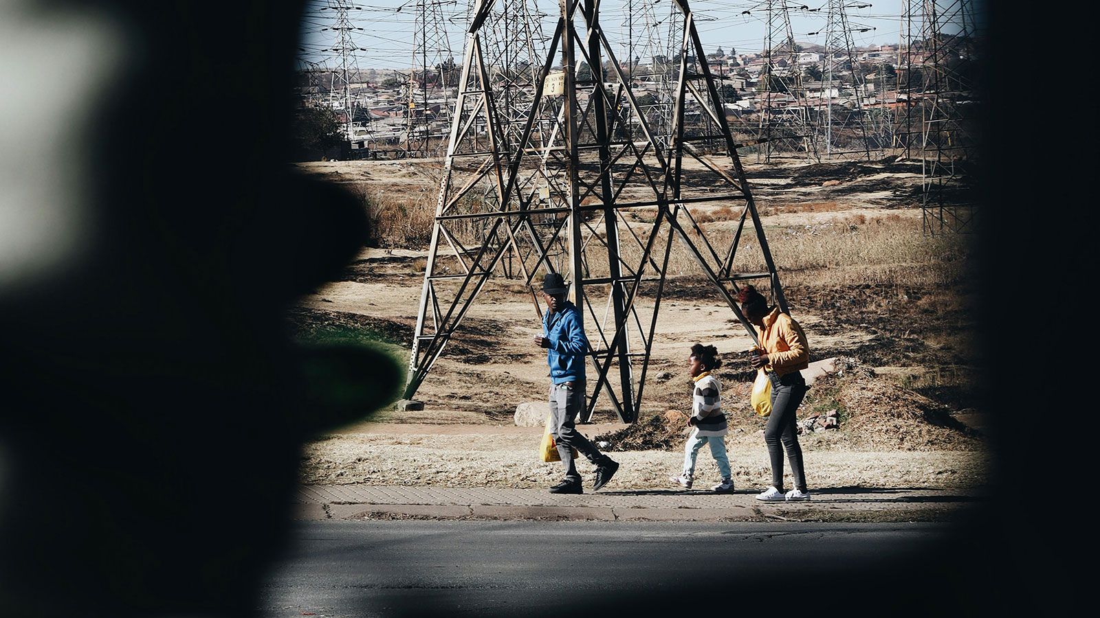 A family walking along a road past electricity pylons