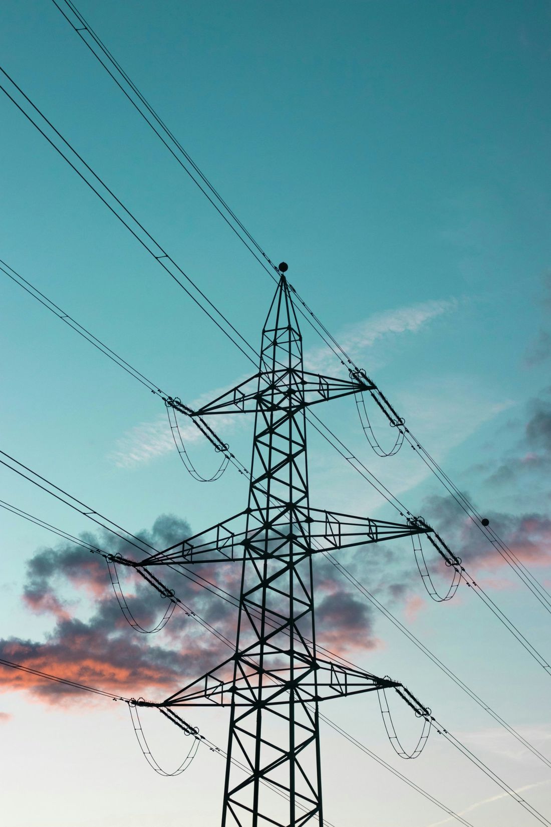 An electricity pylon against a blue evening sky