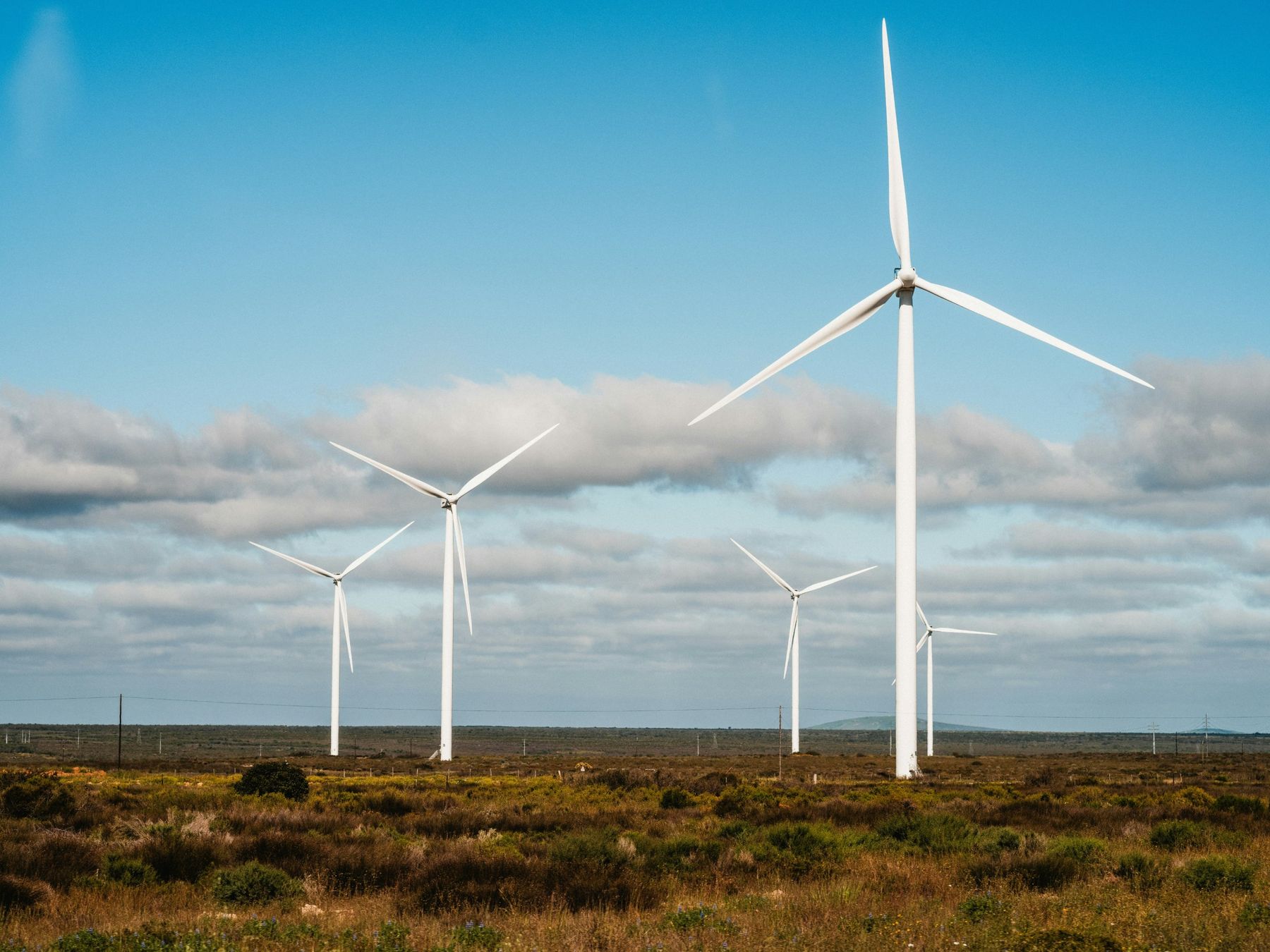 Wind turbines on open scrubland under a blue sky