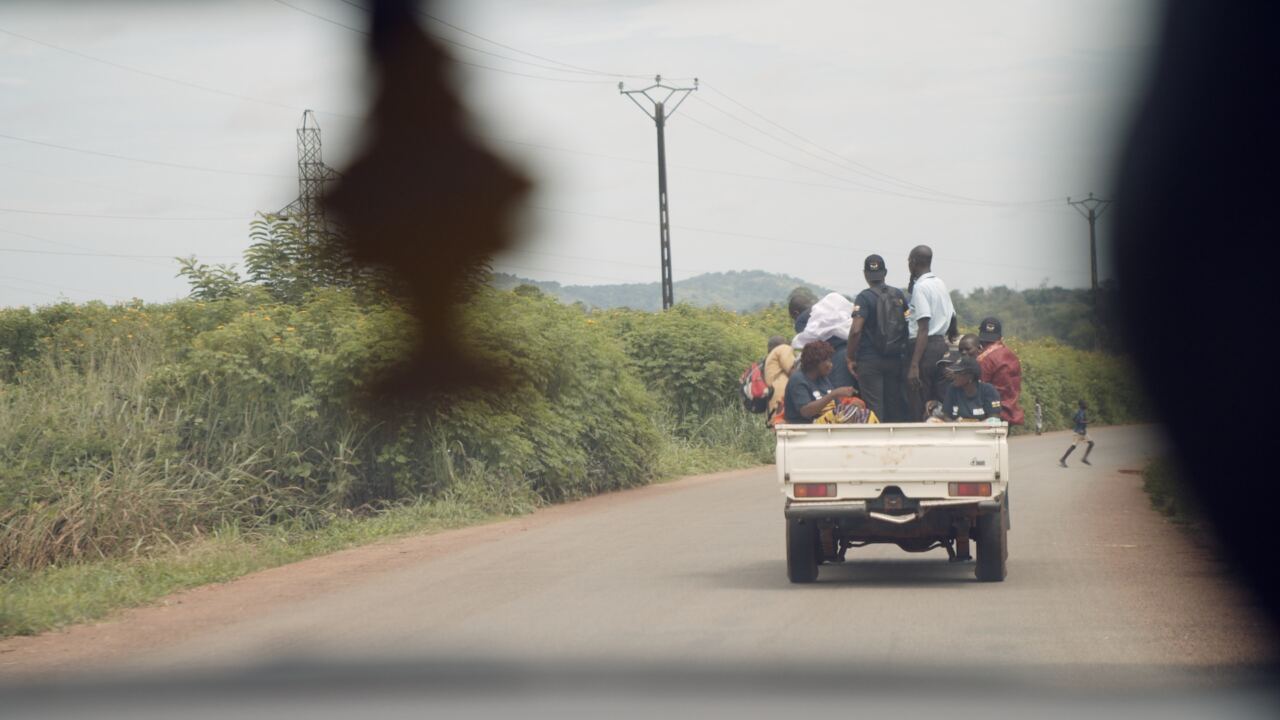 Passengers riding in the back of a pickup on a rural road