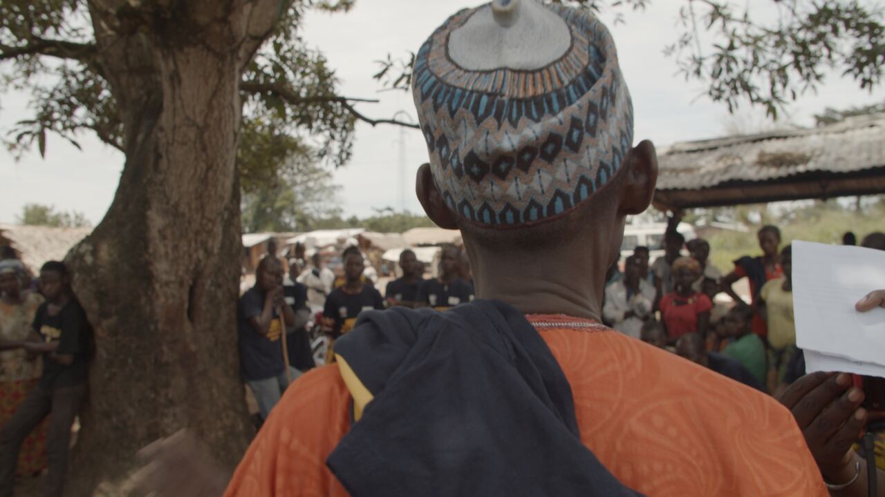 A community leader addressing a crowd under a tree