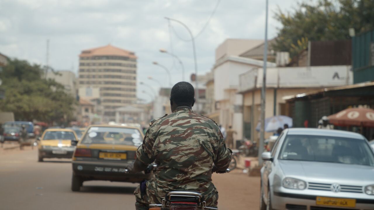 A soldier riding a motorbike through Bangui traffic
