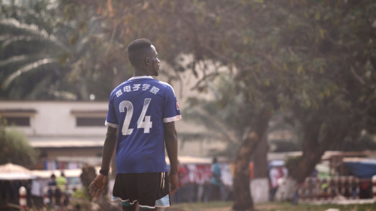 A young man in a football shirt walking down a street
