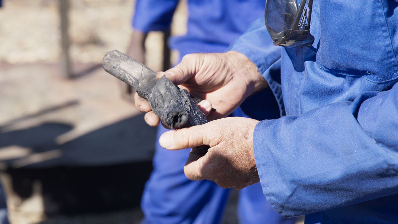 A worker inspecting a piece of charcoal