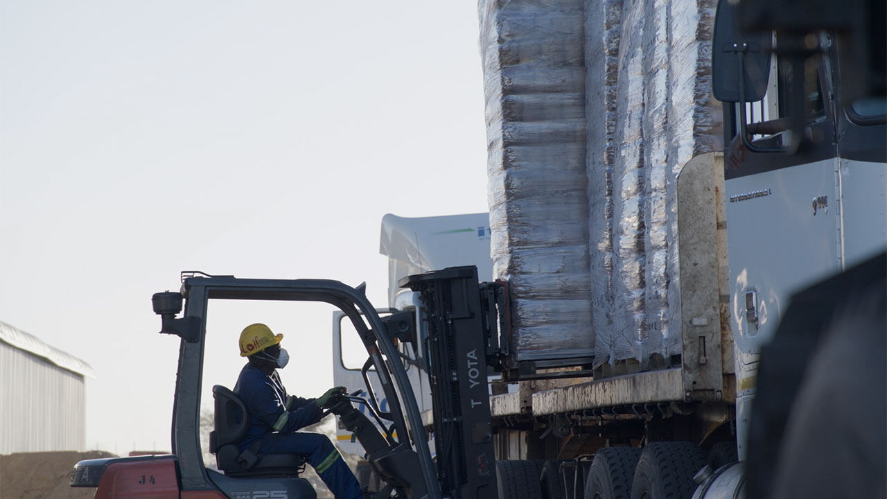 A forklift loading bagged charcoal onto a truck for export