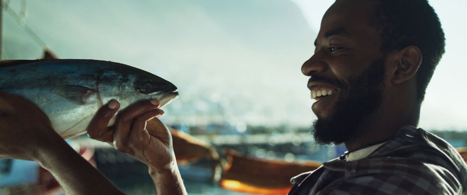 A man smiling as he holds up a whole fish