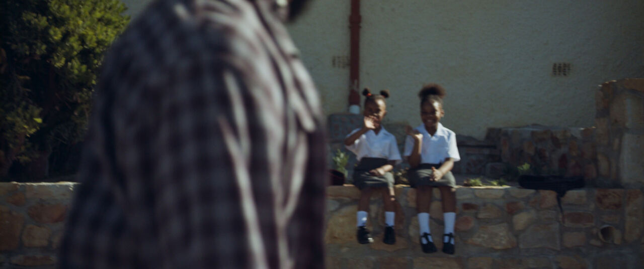 Two schoolchildren sitting on a wall as the man walks past